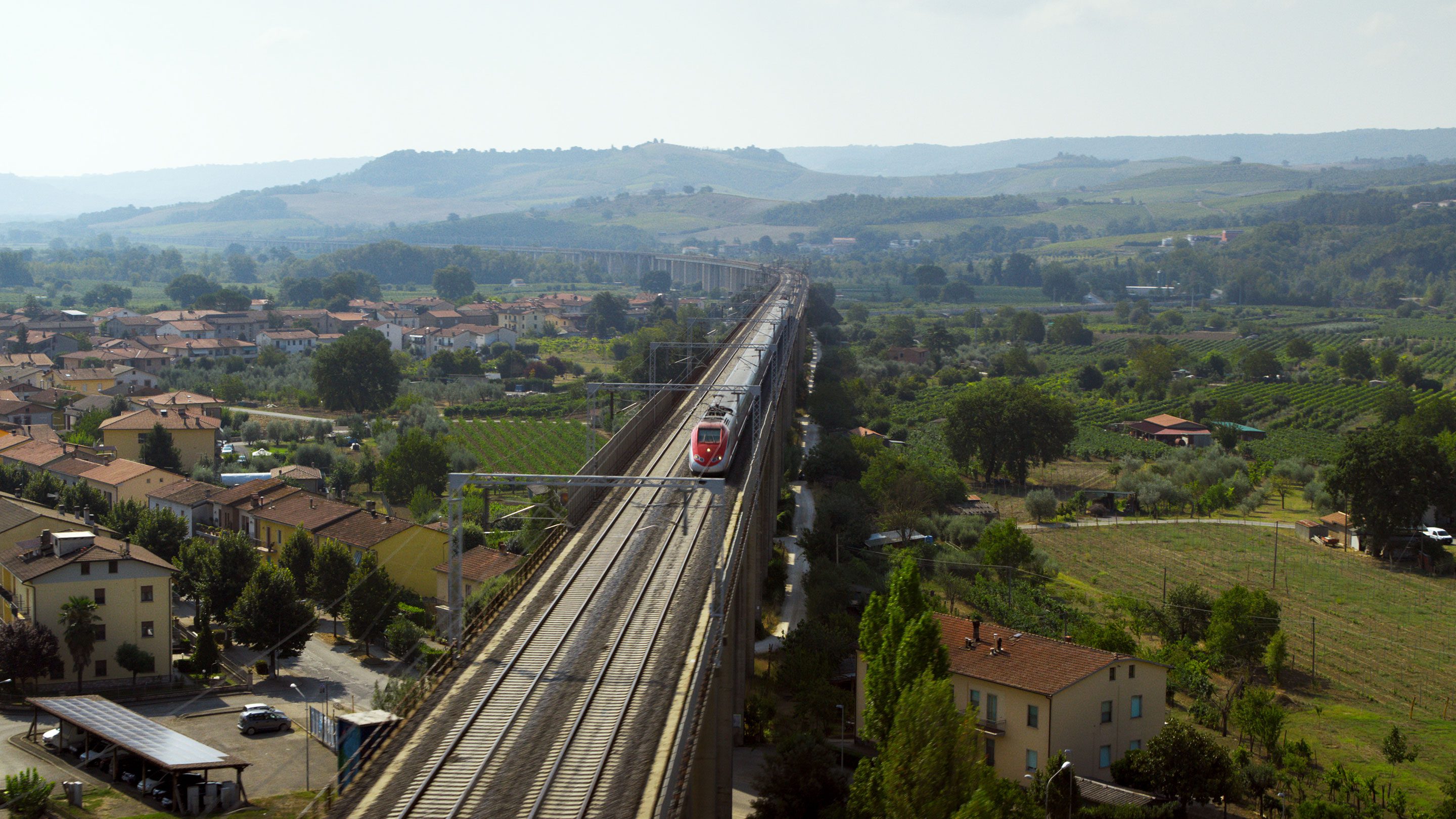 A high-speed train travelling on a track through the Italian countryside. Icomera's SureWAN technology allows its mobile connectivity and applications routers to intelligently connect to multiple cellular and other communications networks simultaneously, aggregating all available capacity to deliver the fastest, most reliable connection possible to a moving vehicle.