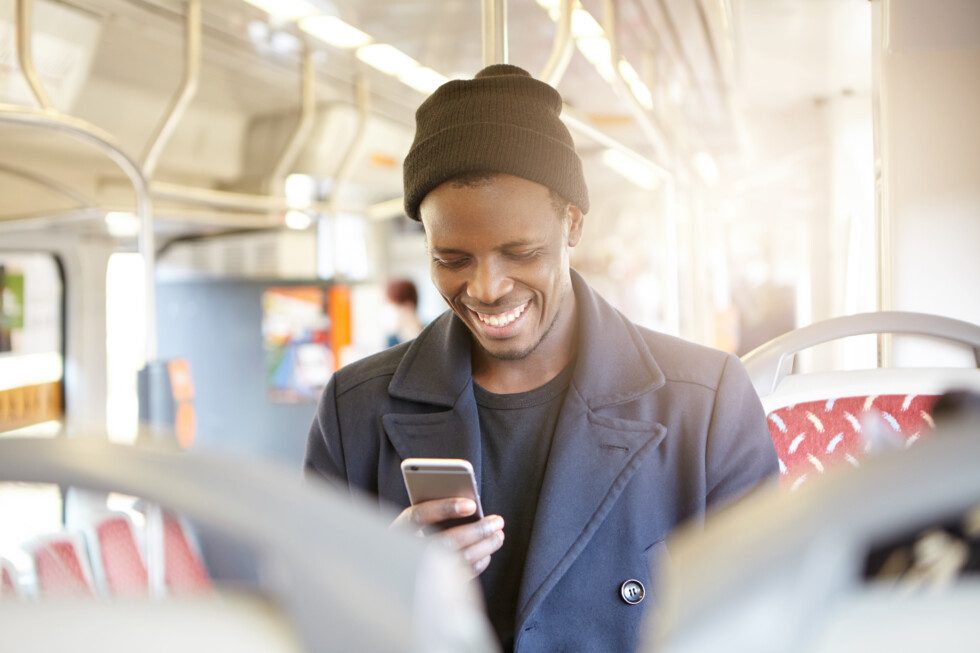 Male passenger on a train holds a smartphone