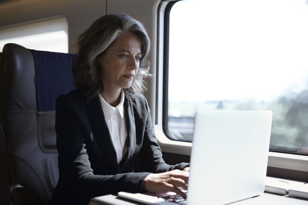 A passenger in business dress is able to work seamlessly on their laptop, thanks to seamless onboard connectivity
