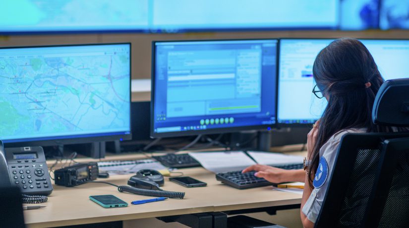 A security officer sits in front of screens monitoring transport activity