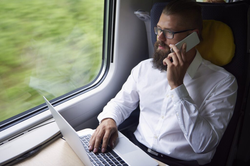 A passenger in business dress is able to work seamlessly on their laptop, thanks to seamless onboard connectivity