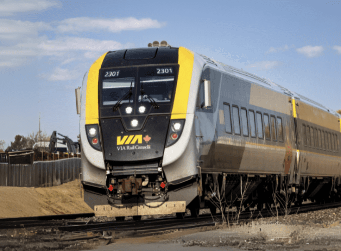 A VIA Rail train travelling through a rural environment