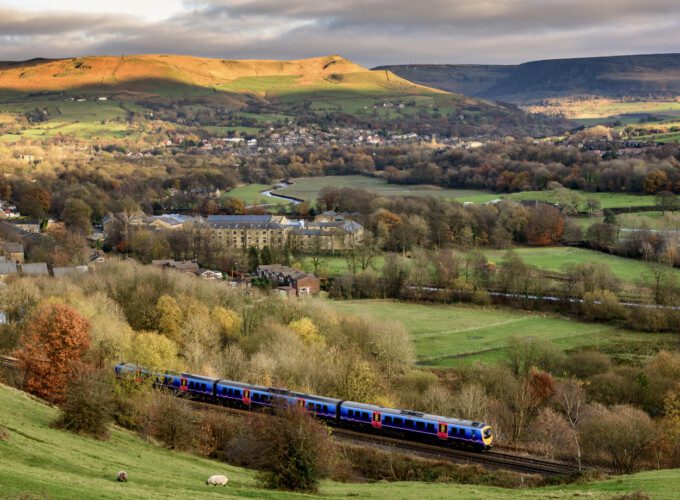 A train travels in the distance. A Uk countryside scene is shown in the background.