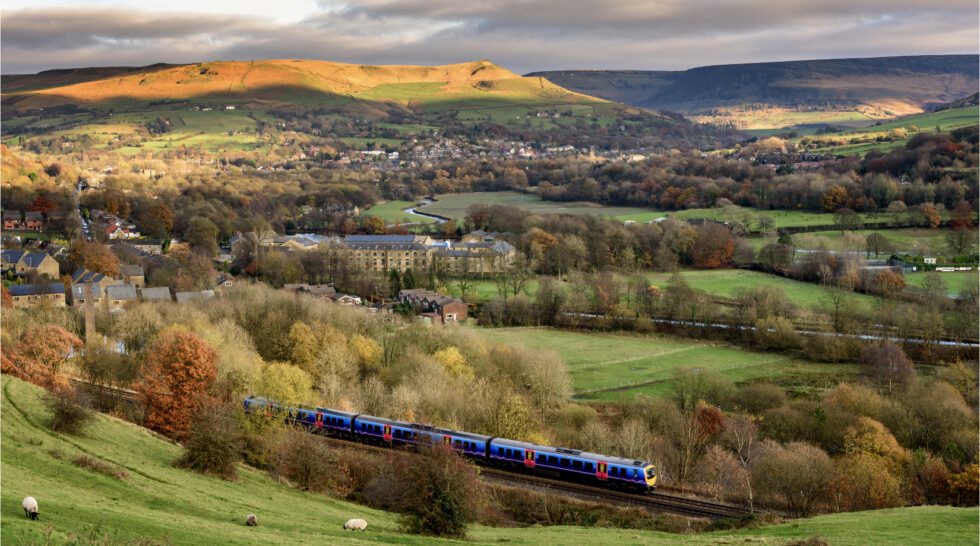 A train travels in the distance. A Uk countryside scene is shown in the background.