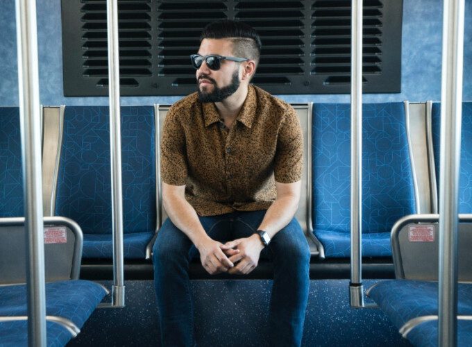 A male passenger wearing sunglasses on a train