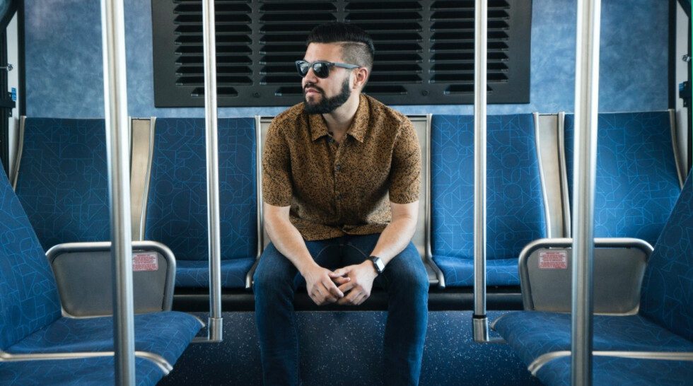 A male passenger wearing sunglasses on a train