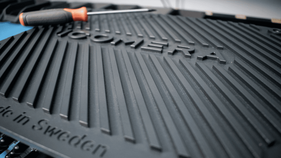 A close up of Icomera's X7 router chassis which is dark grey, with grooved heat-sinks and imprinted with