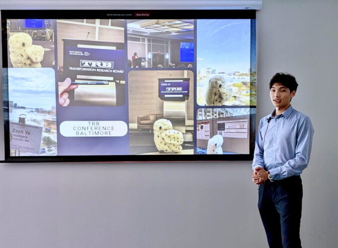 Icomera Intern Zach Ye standing in front of a projected presentation.