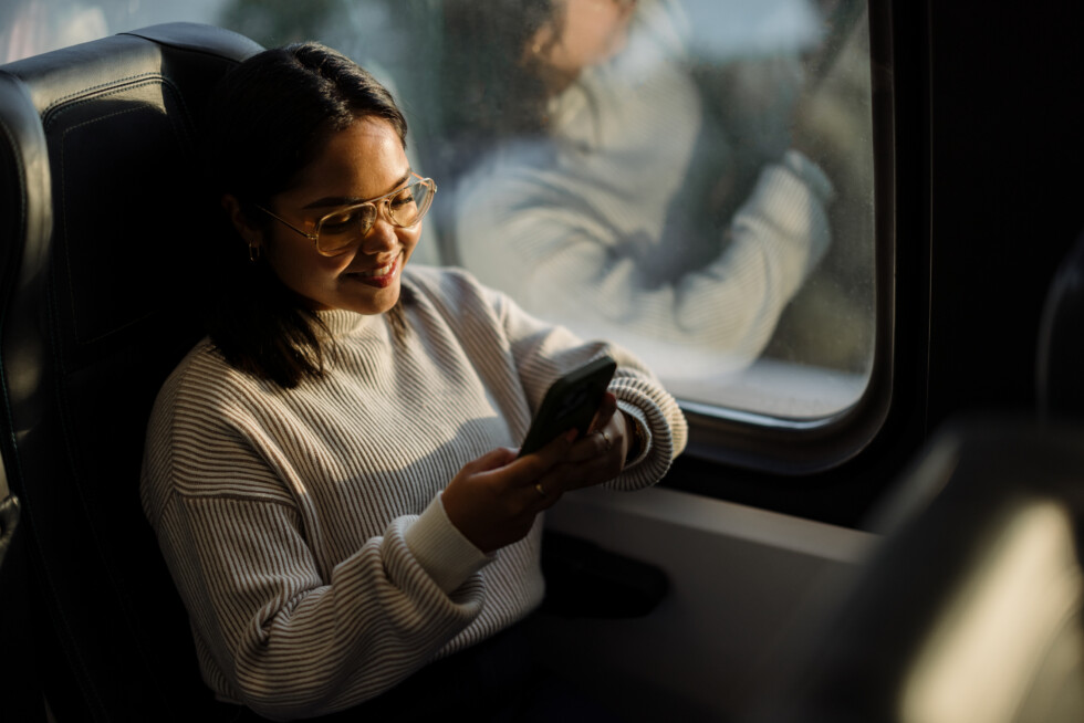 Woman Using Smartphone While Traveling, Smiling and Relaxing on Public Transportation