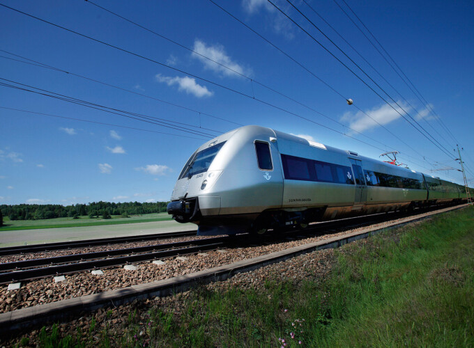 SJ 3000 Train SJ 3000 train operating on Sweden's rail network, travelling through open countryside on an electrified line under clear skies.